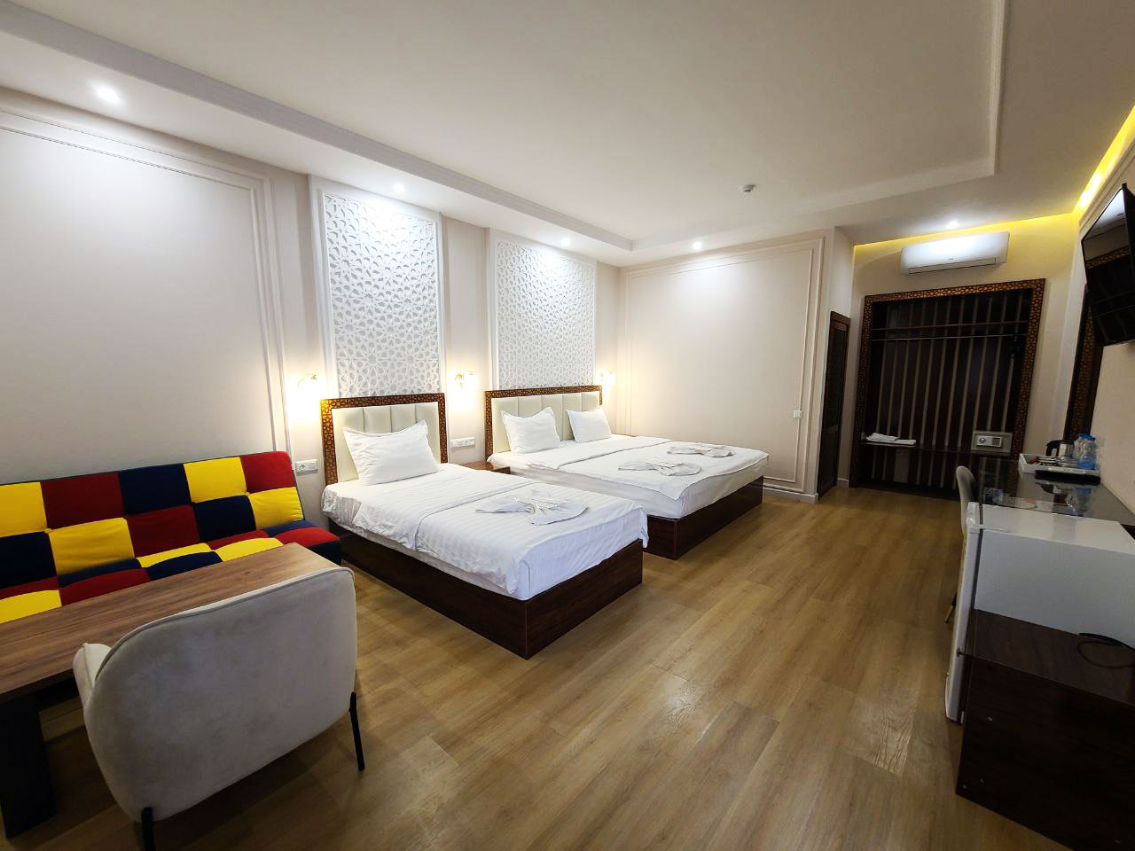 Comfortable deluxe family room in hotel with a double bed, desk, sofa, and coffee table