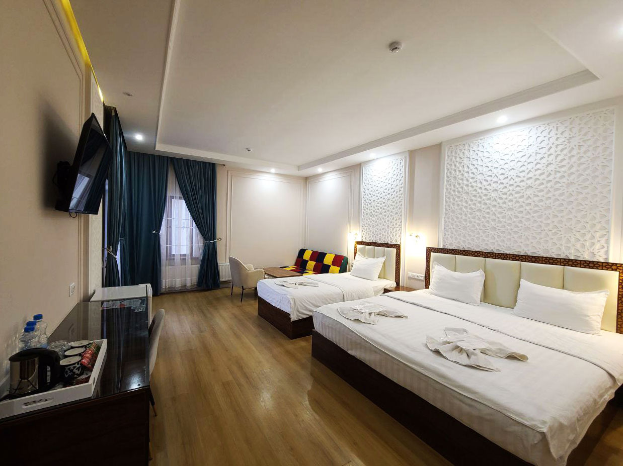 Spacious deluxe family room in hotel featuring a large double bed and a single bed